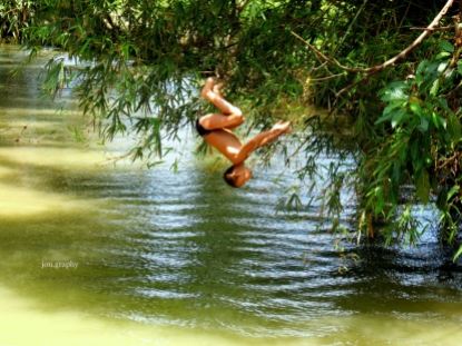 A kid somersaulted into the brown river.